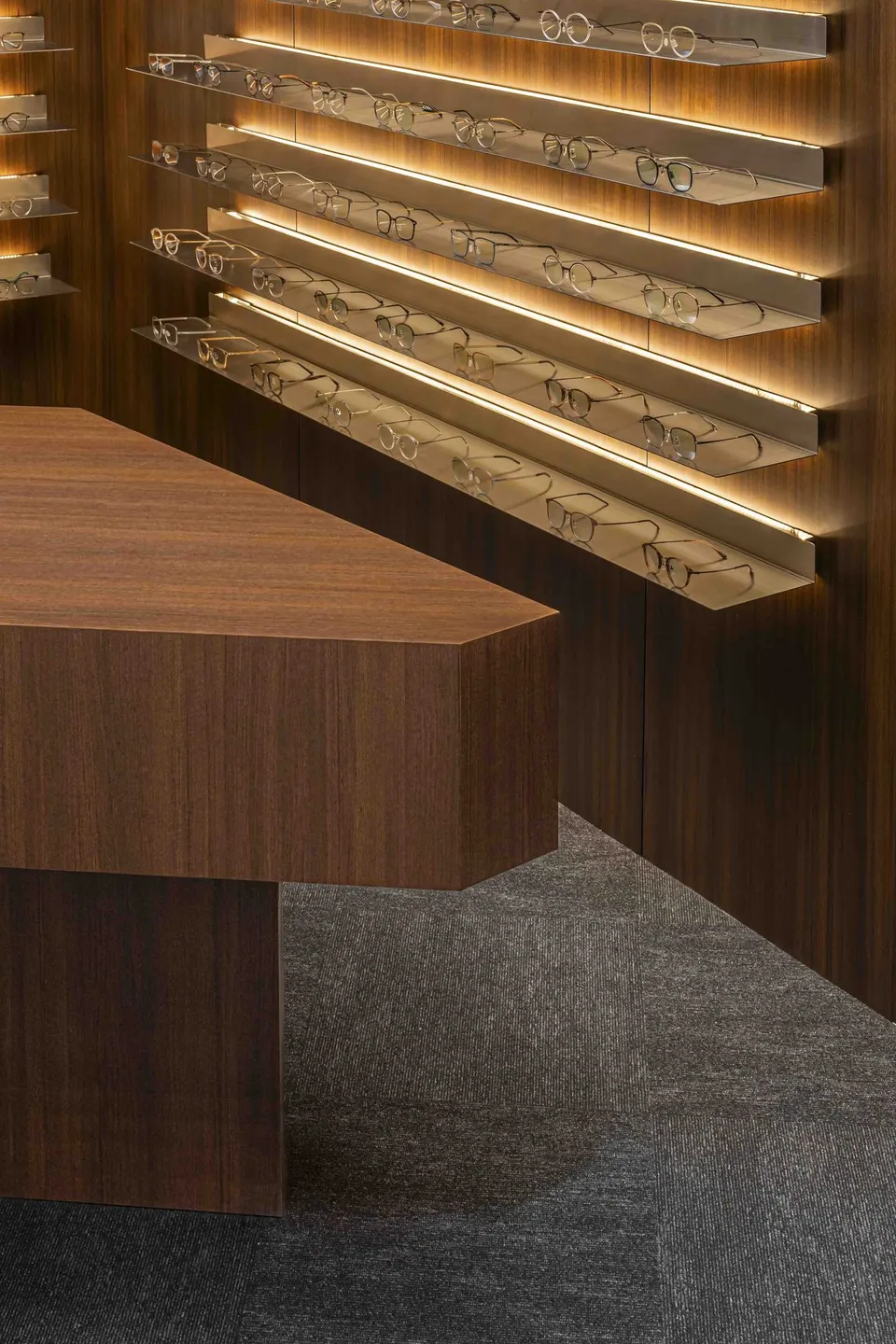 Corner of the timber counter in front of the lit display shelves