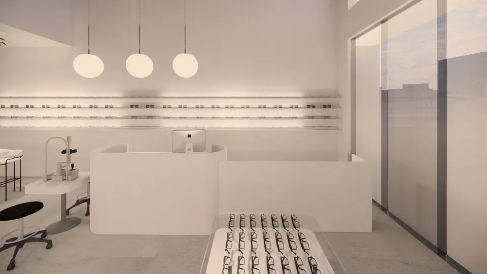 Curved white counter under three globe pendants, with lit shelves of frames behind