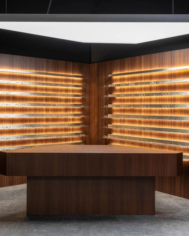 An eyewear boutique glowing in walnut and warm light.